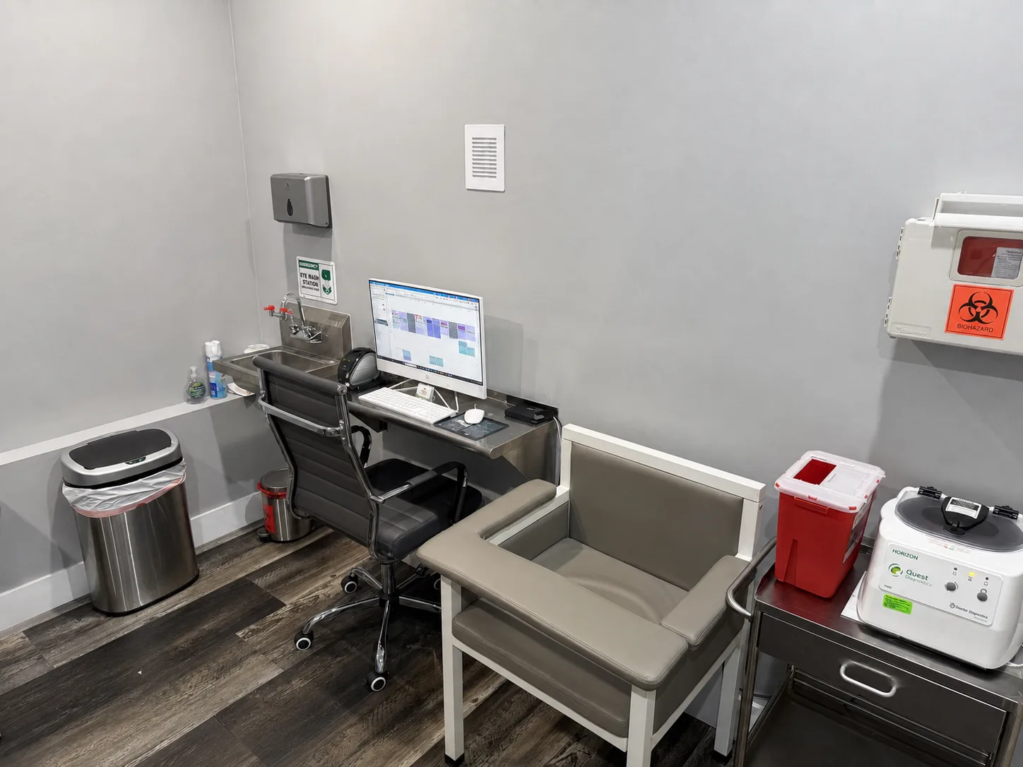 Real clinical-station photograph retouched with AI to remove visible data and small personal items without altering equipment or furniture.
